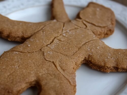Human-shaped spiced cookies with coarse sugar crystals on white plate