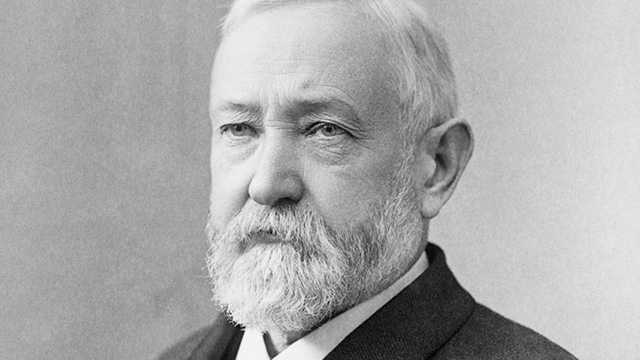 Black and white portrait of an older man with full beard wearing formal dark jacket