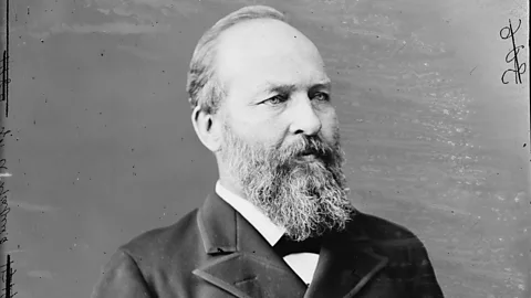 Black and white portrait photograph of bearded man in formal suit and bow tie