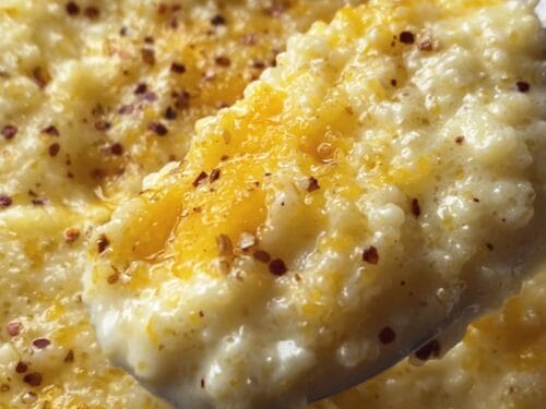 Close-up of creamy cornmeal dish with melted butter and red pepper flakes