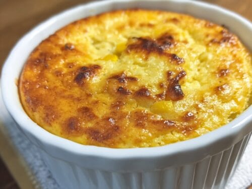 Baked golden-yellow custard with browned spots in white ceramic ramekin