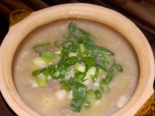 Creamy soup in ceramic bowl topped with chopped green onions