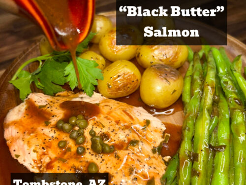 Cooked salmon fillet topped with capers, served with roasted potatoes, green beans, and cilantro on wooden board