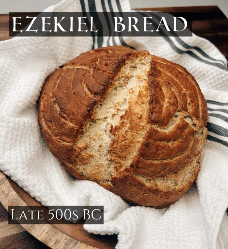 Round loaf of brown bread with scored top on white linen cloth