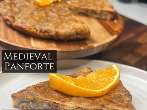 Sliced spiced cake topped with candied orange, served on white plate and wooden board