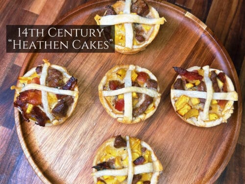 Five round pastries with white lattice strips and dark meat filling on a wooden plate