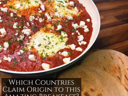 Three eggs poached in red tomato sauce, topped with crumbled white cheese and green herbs, in shallow white pan