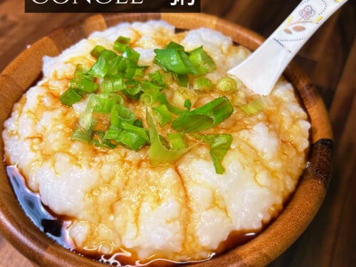 Congee served in a wooden bowl, topped with sliced green onions and oil, with spoon