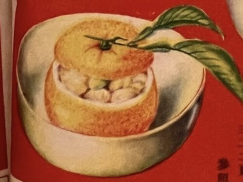 Hollowed citrus fruit filled with diced chicken, topped with leaf garnish