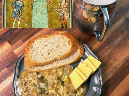 Tin plate with thick vegetable stew, bread slice, and butter pat beside a drinking vessel on wood