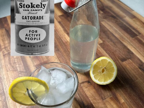 Clear beverage in glass with ice and lemon slice, bottle with red-and-white stopper, vintage can label visible
